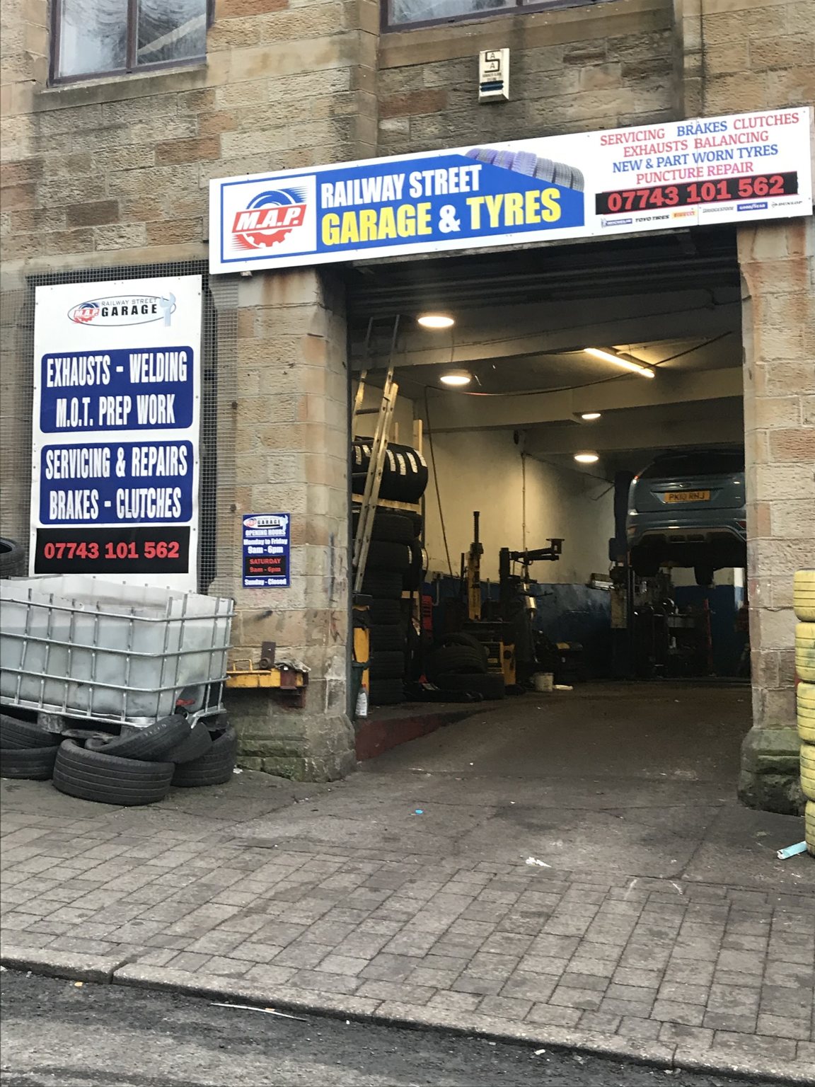 The front of Railway Street Garage and Tyres, with the blue M.A.P. sign over the open workshop door and a car up on the lift inside
