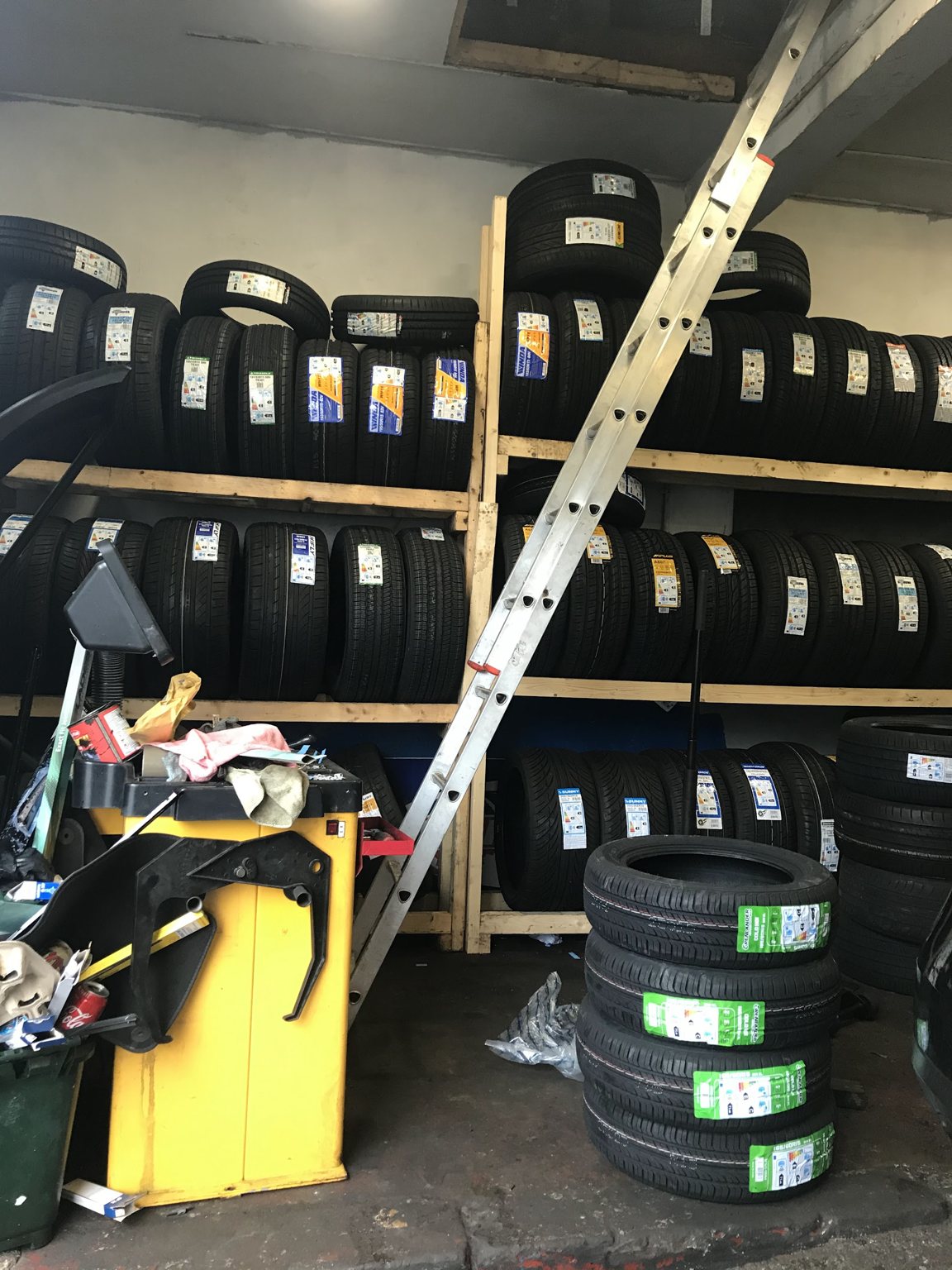 Wooden racks stacked with new tyres in the workshop, next to the tyre changing machine