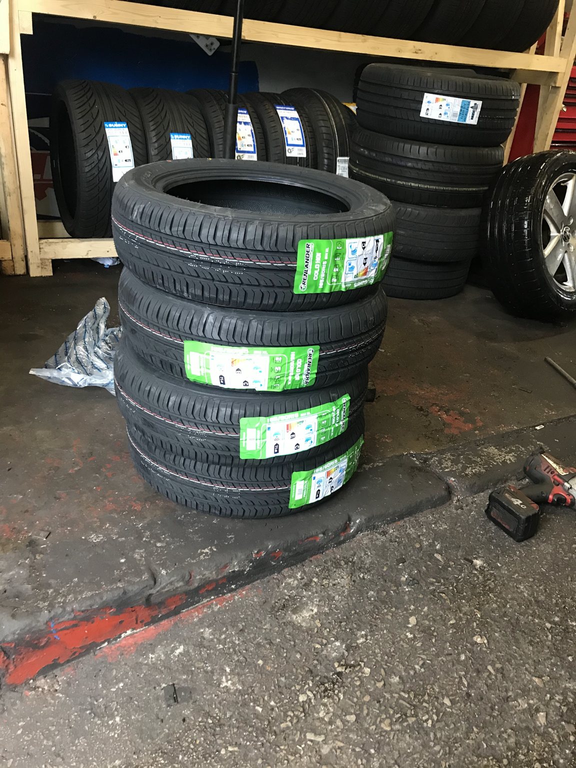 A set of four new tyres stacked on the workshop floor, ready to fit